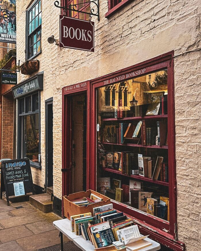 Livraria acolhedora e grandiosa com livros expostos no exterior, apresentando uma fachada encantadora e uma atmosfera calorosa e convidativa.