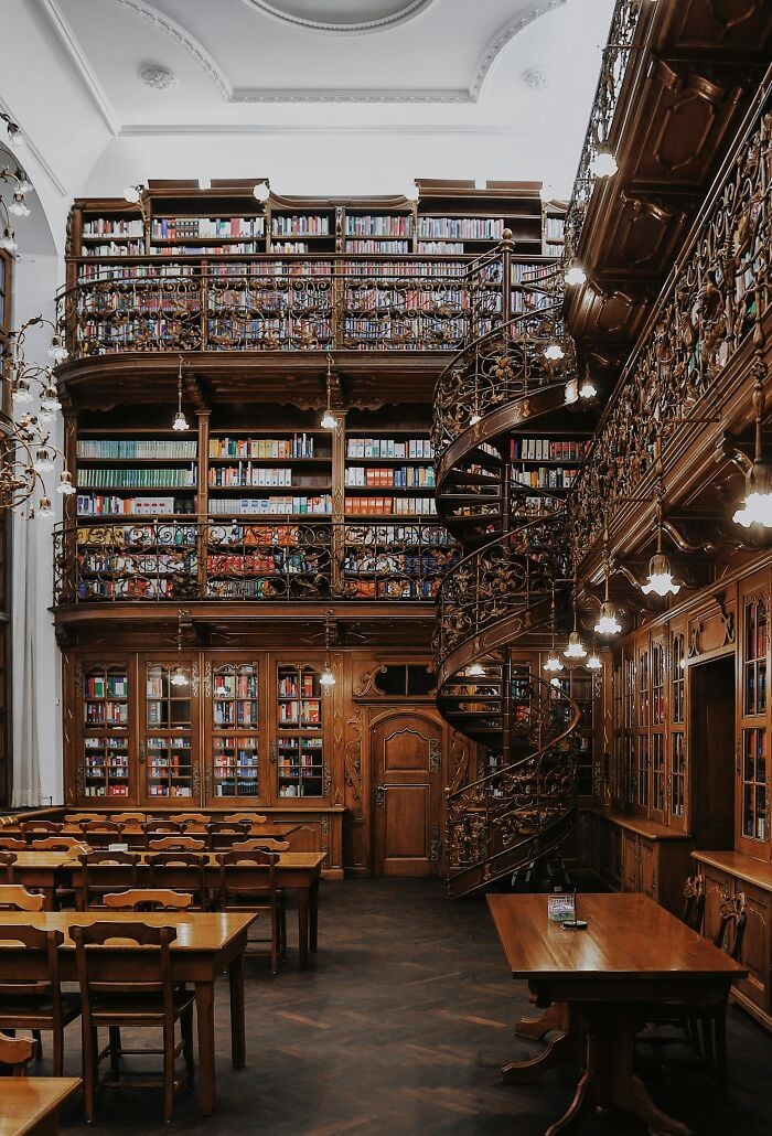 壮大な図書館の内部には、木製の棚、螺旋階段、世界中の本が並ぶ居心地の良い読書テーブルがあります。