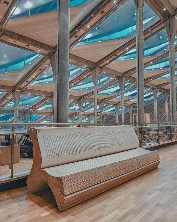 Banco em forma de livro aberto dentro de uma biblioteca moderna e grandiosa com arquitetura de vidro e metal de todo o mundo.