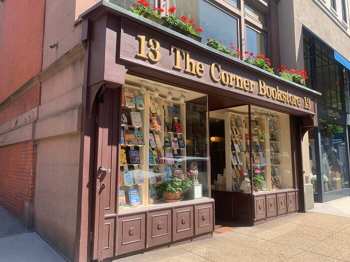Exterior encantador de livraria com floreiras, mostrando uma livraria acolhedora e mágica de todo o mundo.